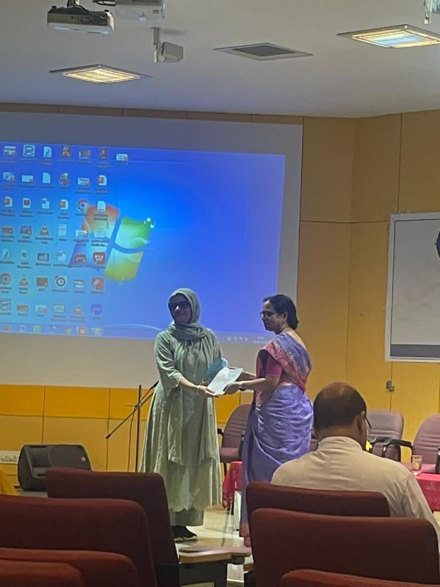Dr. Mariam Anjum receiving award from faculty member in lecture hall